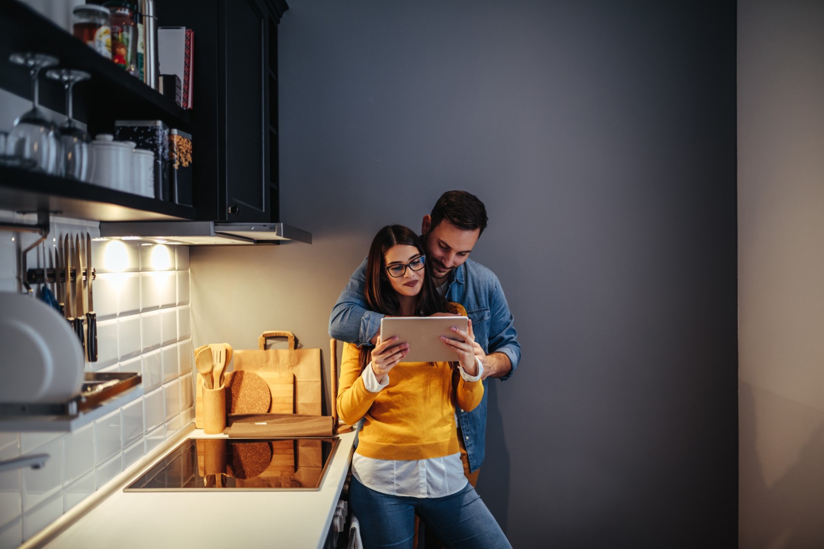 A young couple looking at tablet computer in apartment kitchen